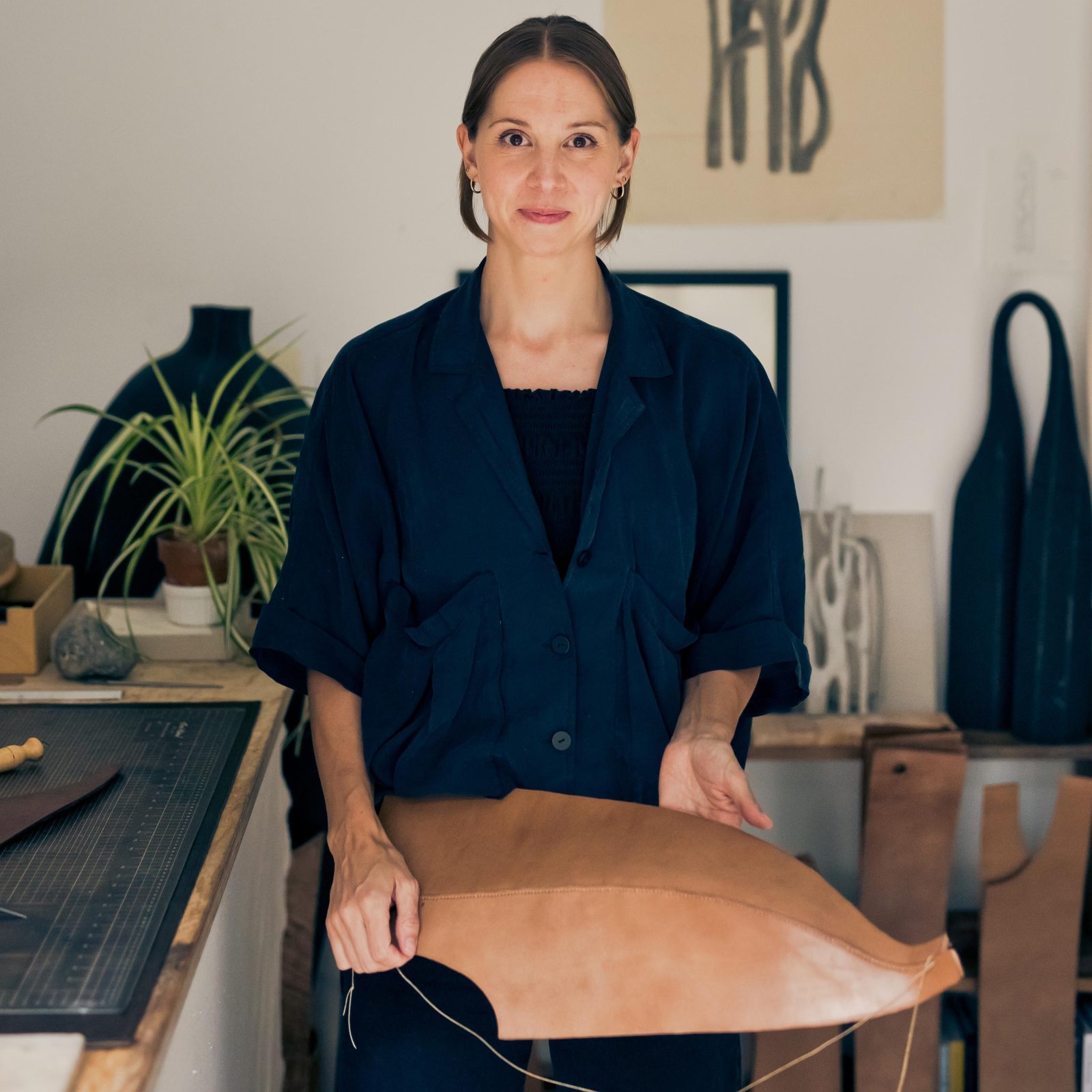 woman in a studio holding a leather sculpture