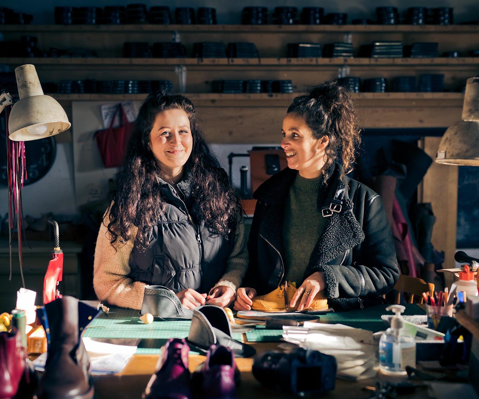two women at a workbench with leather