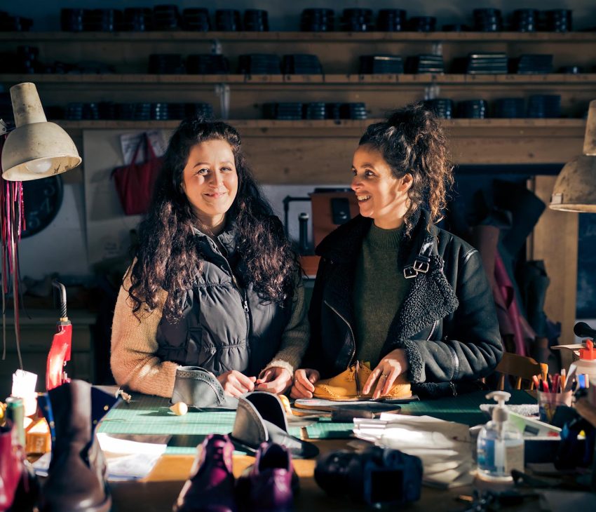two women at a workbench with leather