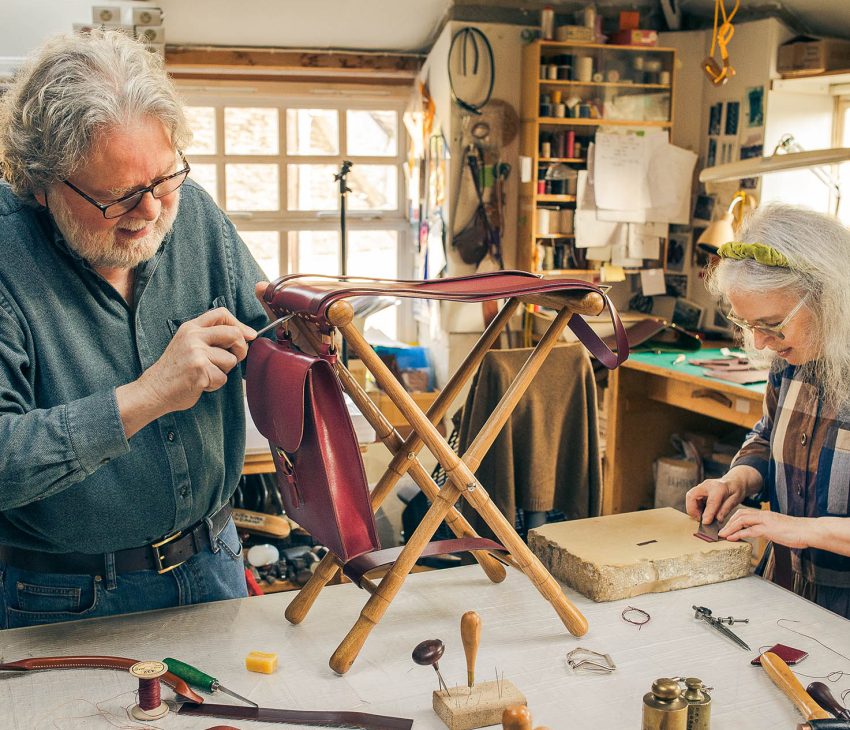 man and a woman work together on a chair using leather