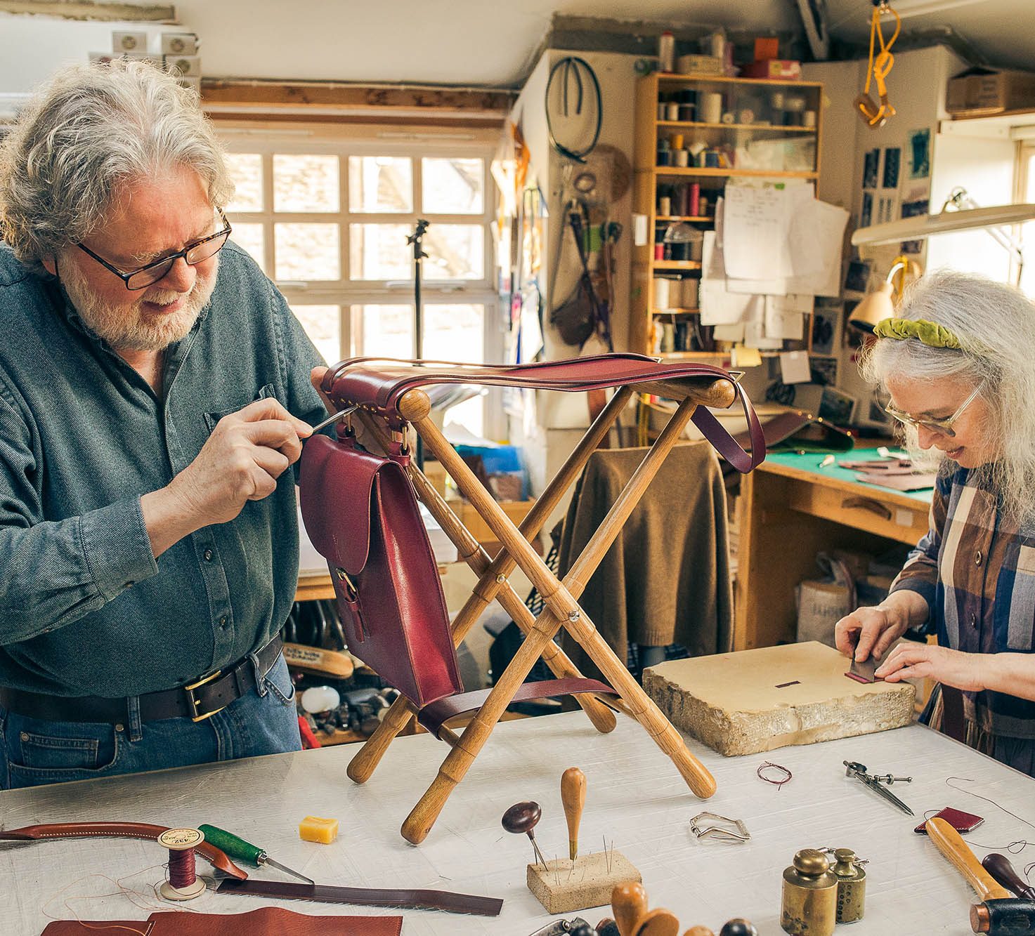 man and a woman work together on a chair using leather