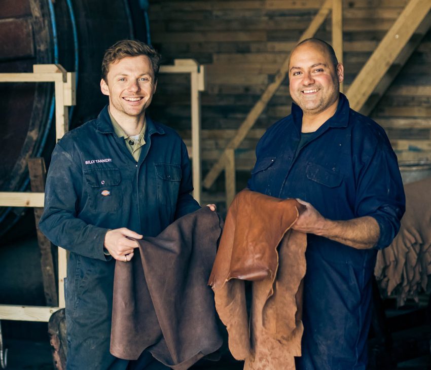 two men in a tannery holding hides