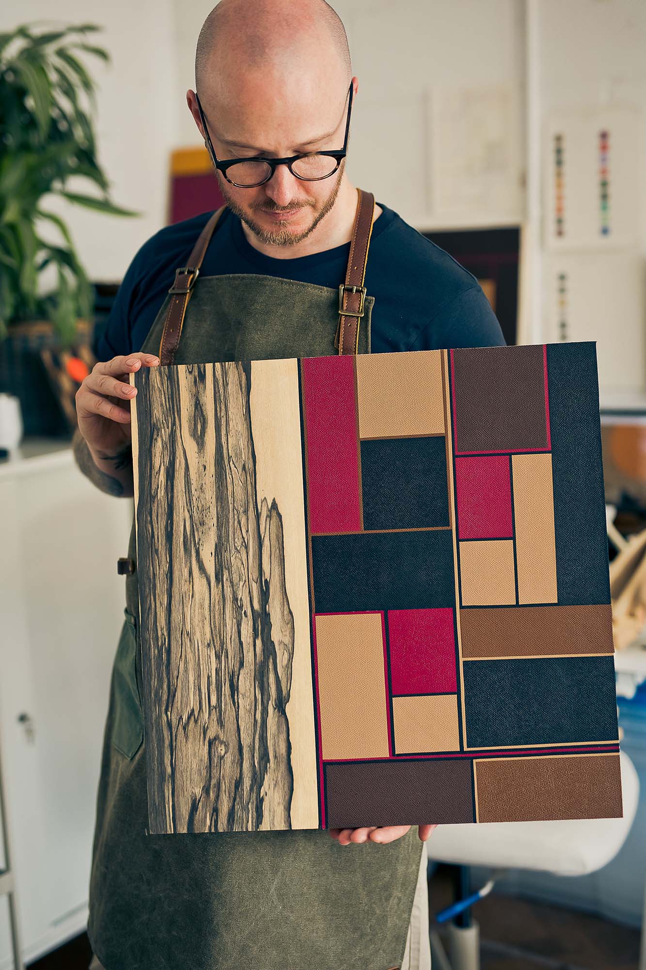 man holding leather and wood artwork
