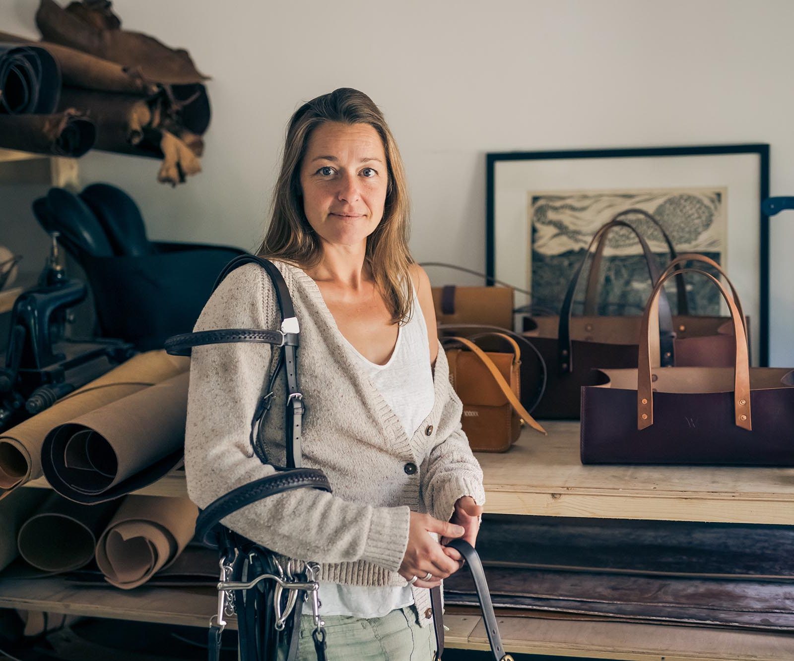 woman holding leather accessories with bags in the background