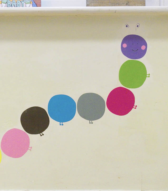 A multi-coloured drawing of a caterpillar on a wall, each section of its body is a coloured circle.