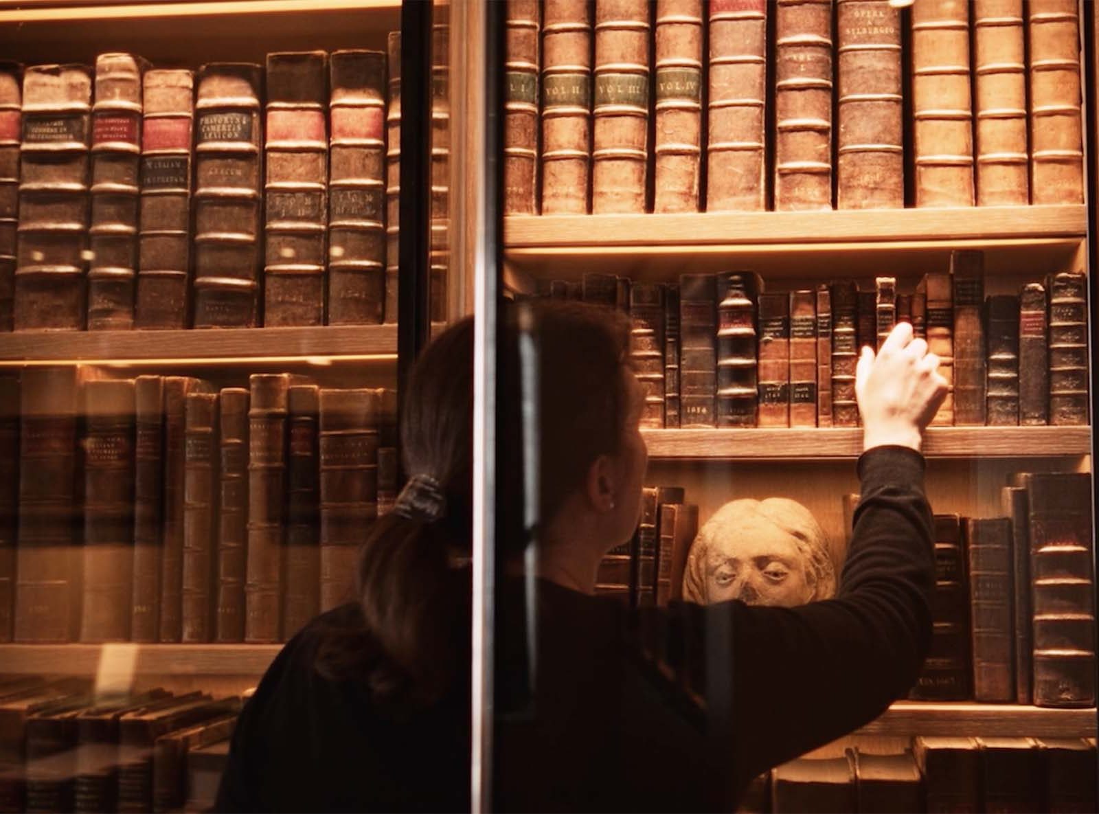 woman selecting a book from a library case