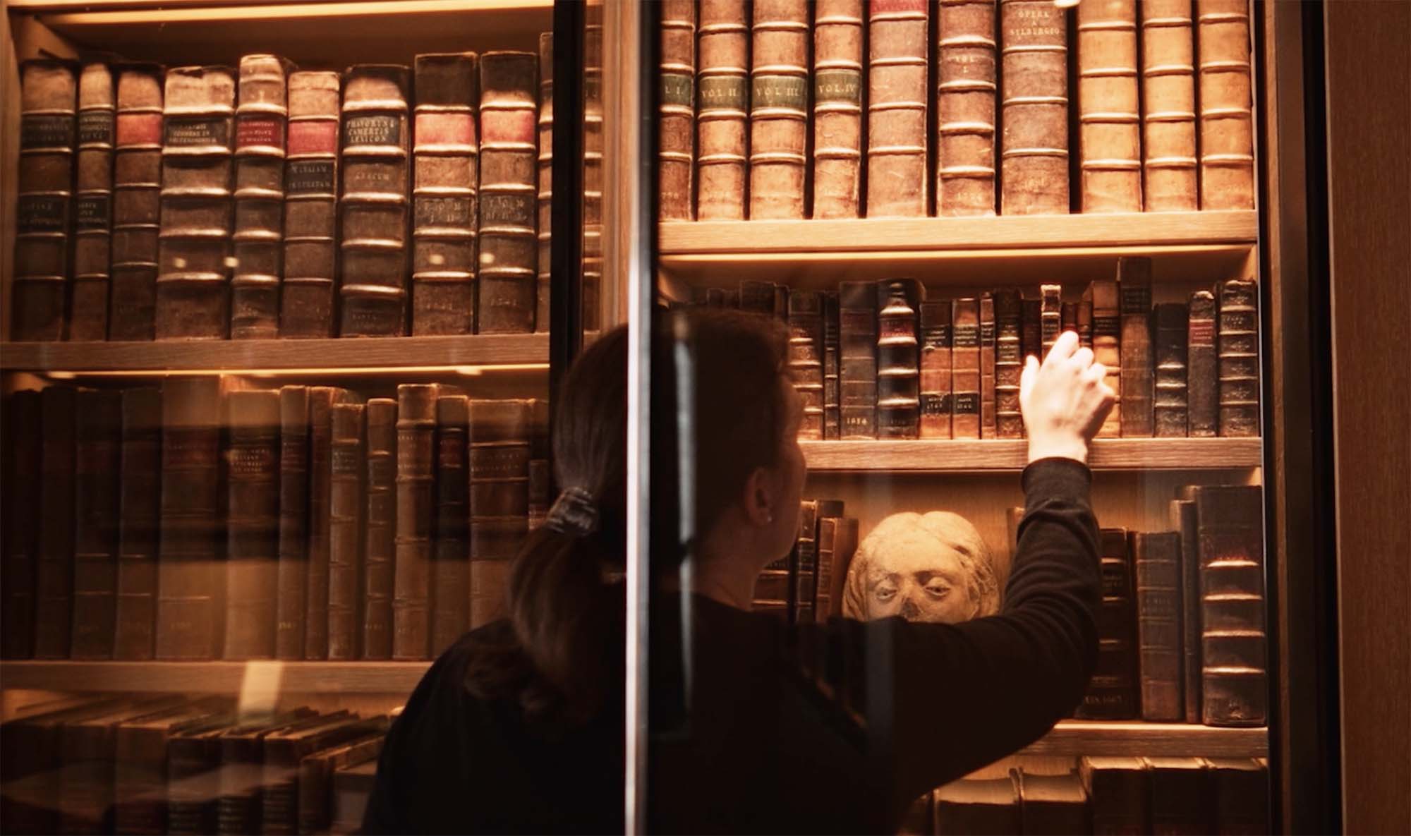 woman selecting a book from a library case