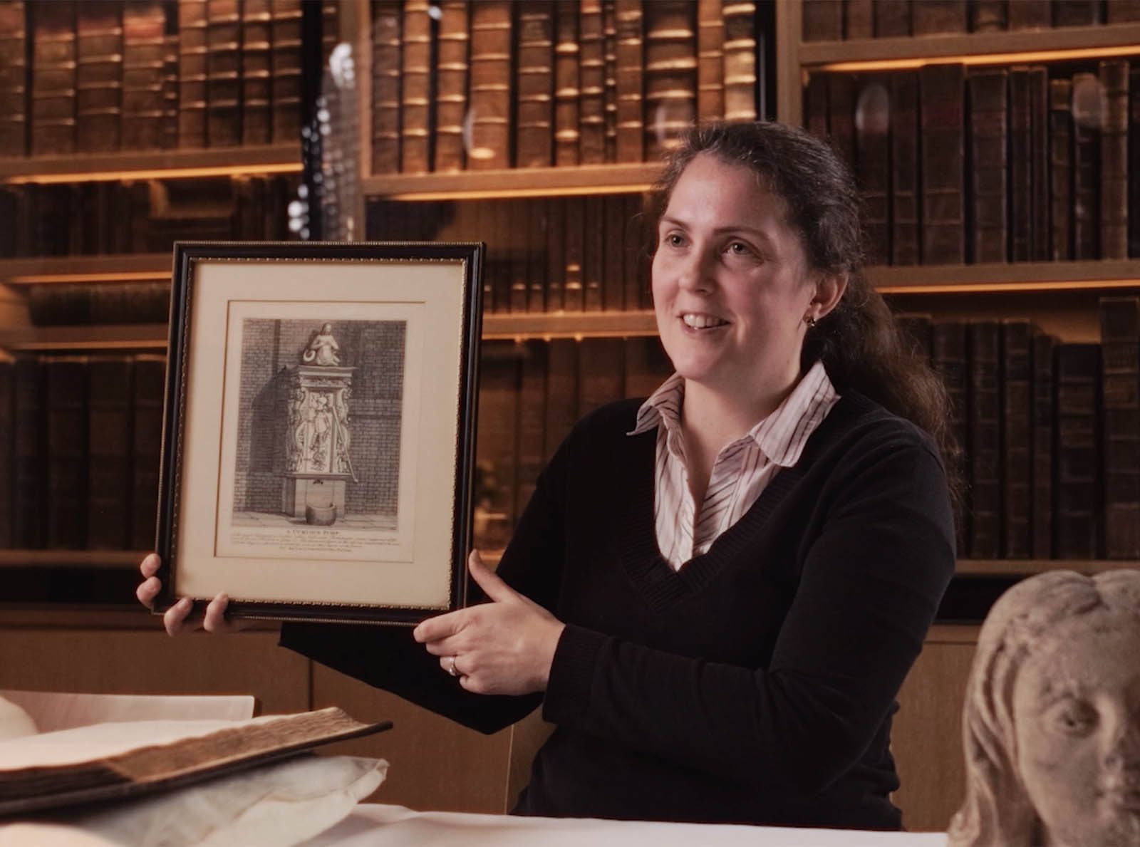 woman holding a framed print in a library