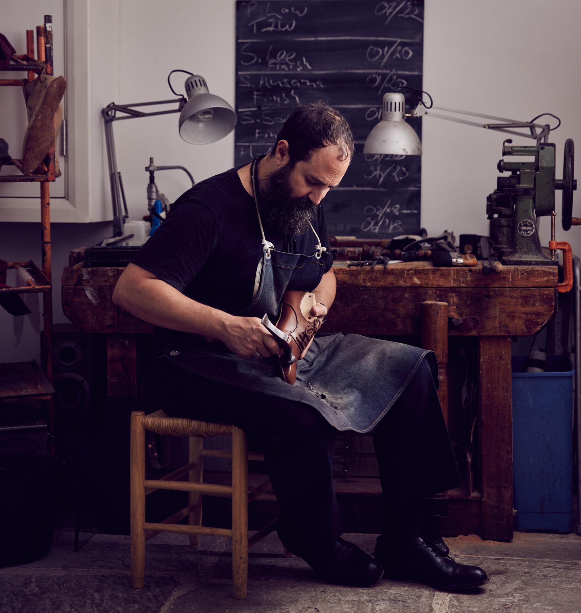 a man sitting on a chair making a shoe