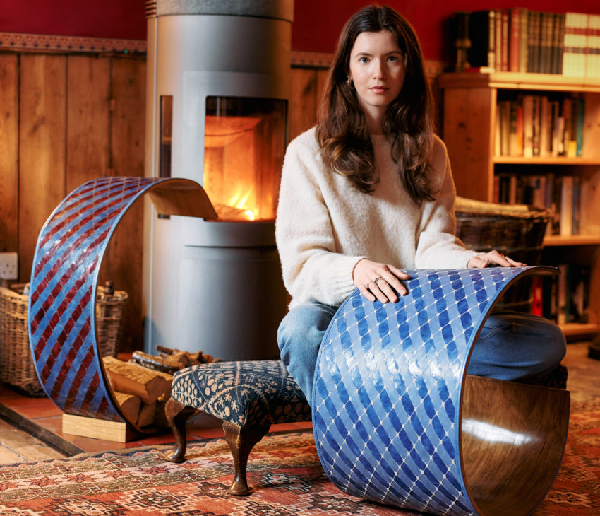 woman holding a leather artwork with a fire in the background