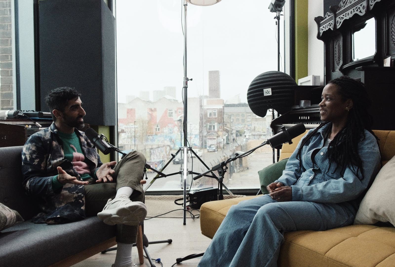 two people sitting on sofas talking into microphones