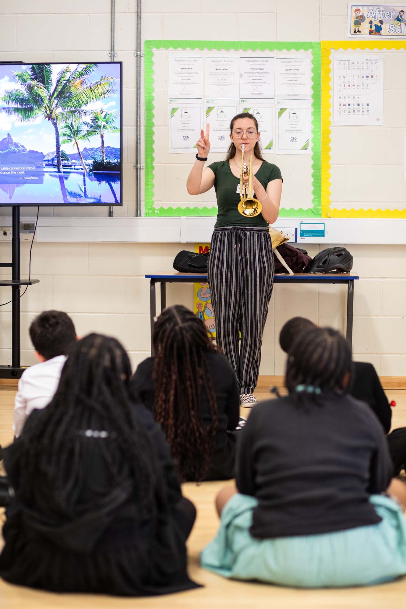 a woman teaching school children how to play the trumpet