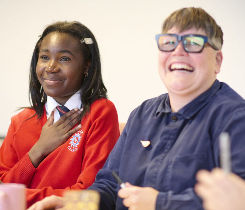 a girl in a red jumper sitting next to a woman with glasses