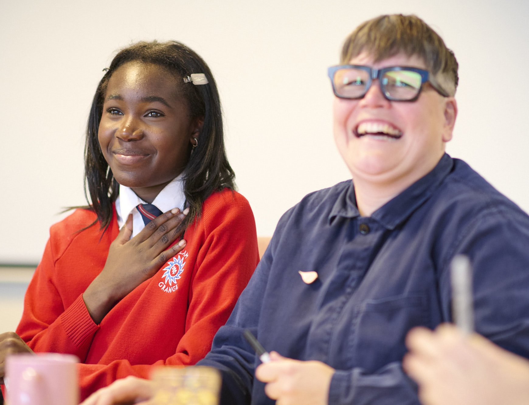 a girl in a red jumper sitting next to a woman with glasses