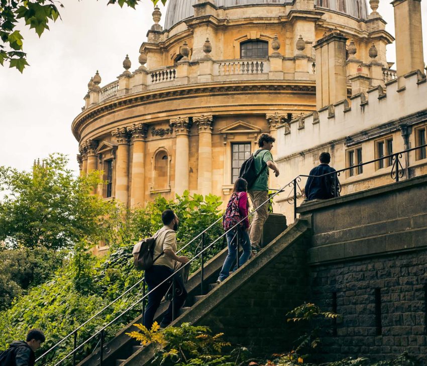 school children walking up stairs with a domed building in the background